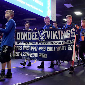 Dundee freshman Braeden Davis carries the Michigan flag, while seniors Christian Killion, Dennis Root, and Jaxon Guinn carry the Dundee Viking banner showing 11 state titles in the grand march at Wings Event Center February 29, 2020. The three seniors were part of the wrestling club at a young age. Dundee won its 12th title beating Richmond 44-18.