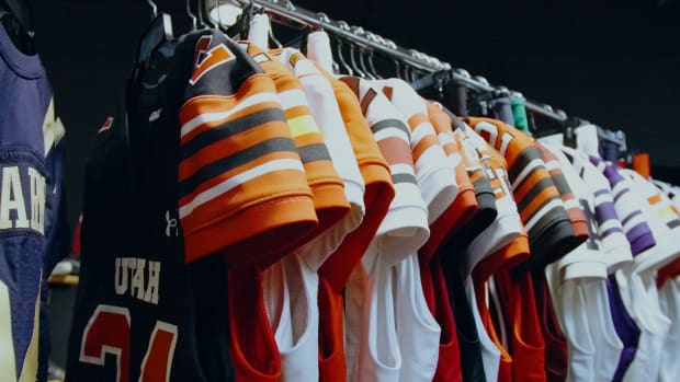 Eight college football jerseys hang on a rack in an Under Armour photo shoot.