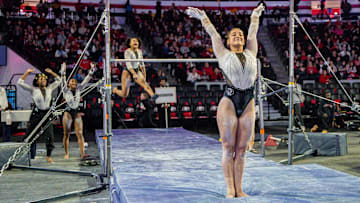 United States; Gymnast Mara Titarsolej stands with a grin after finishing her bar routine.