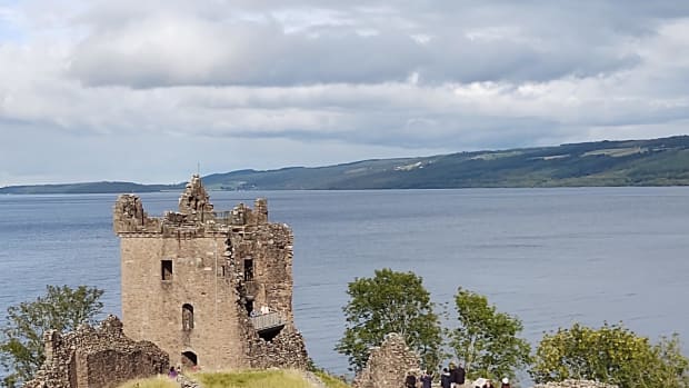 A gray stone castle overlooking a blue lake.