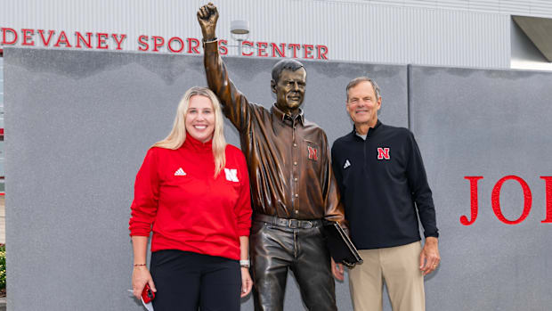 Former Nebraska volleyball coach John Cook poses next to his stature with his successor Dani Busboom Kelly.