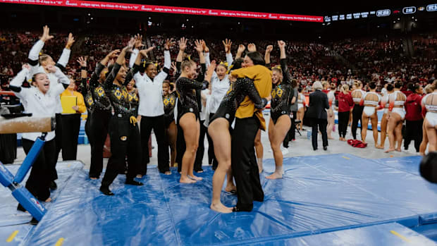 Helen Hu hugs her coach as her teammates hold up 10 fingers to celebrate her routine. 