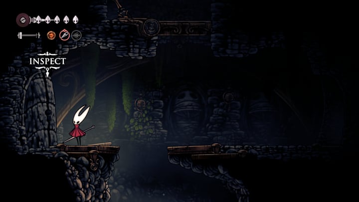 Hornet standing next to a locked door in a dark cave.