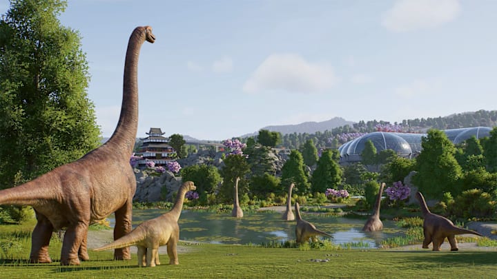 Tall dinosaurs on a field and in a pond with futuristic buildings in the background.