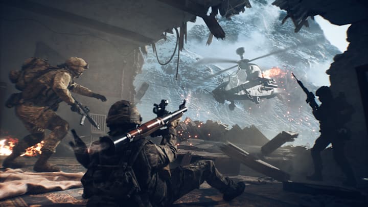 A soldier lays prone aiming an RPG at an attack helicopter strafing a hole in the building in Battlefield 6