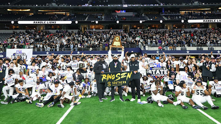 Richmond Randle head coach Brian Randle hoist the trophy while surrounded by coaches and players following their victory over South Oak Cliff in Texas 5A Division 2 title game at AT&T Stadium.