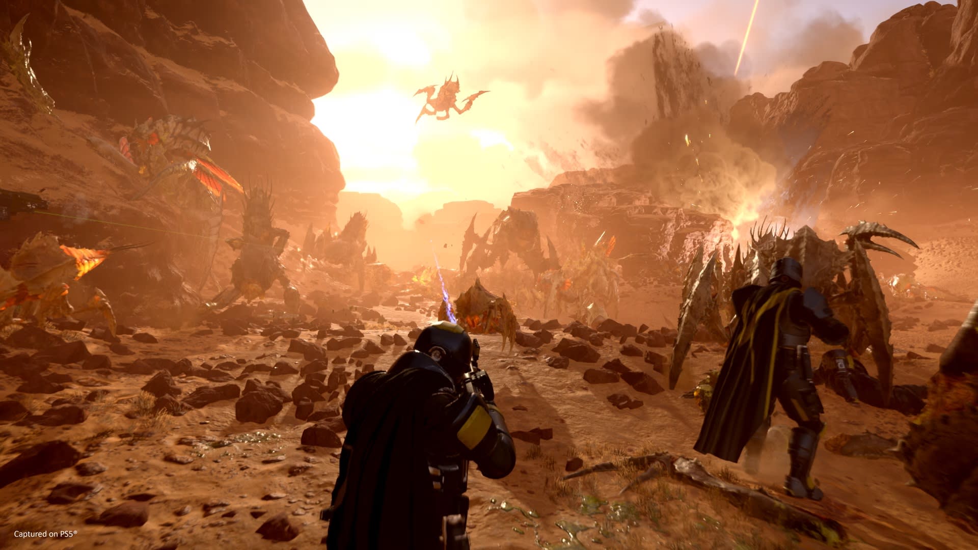 Helldivers 2 screenshot showing human soldiers battling bugs on a rocky desert world.
