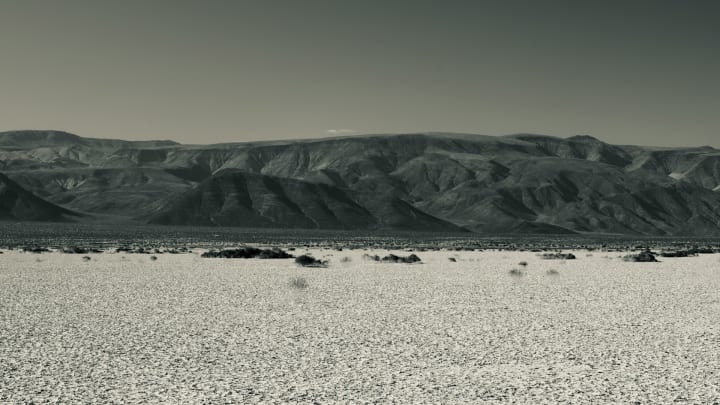 Cracked mudflats in the Panamint valley within Death Valley national park, with the mountains in the background. 