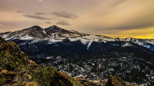 A beautiful scene of snow covered mountains and some greenery in the foreground.  