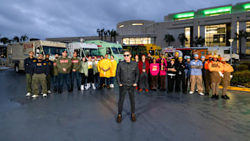 Nishaan, Fat Kid Food Co., Stop Drop N Roll, Rising Tiger, Good Fortune Company, Eat My Biscuits, Burger Walla, G’s Cheesesteaks and Cooking with Que team members in front of their trucks with host Tyler Florence, as seen on The Great Food Truck Race, Season 18.