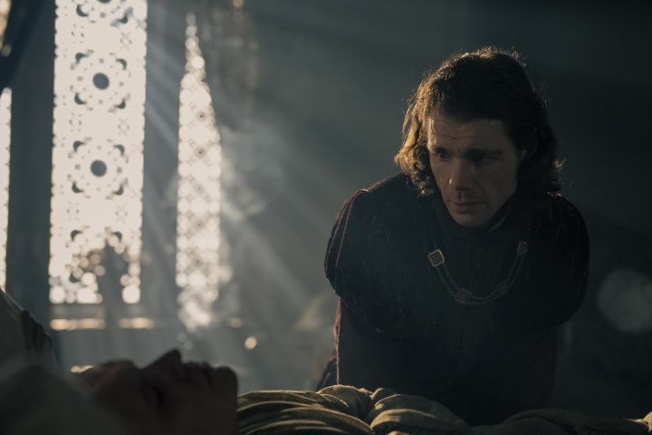 Larys Strong sits at the bedside of King Aegon II Targaryen.