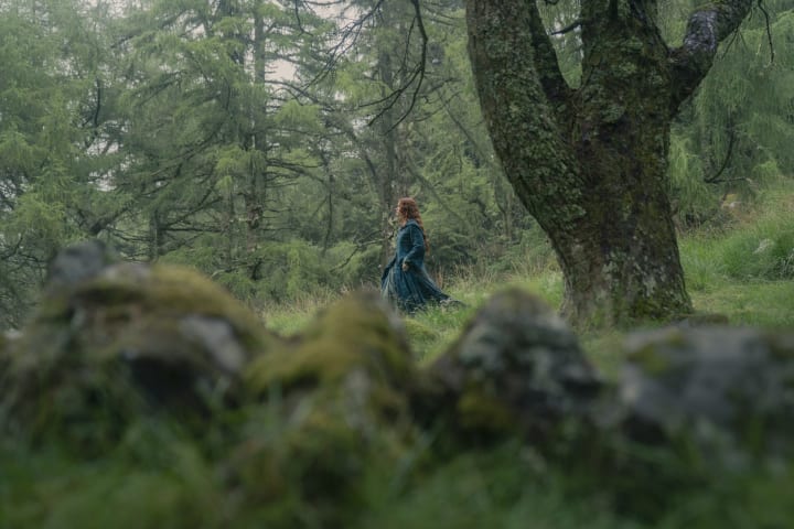 Alicent Hightower walks through a mossy forest. She's in one of her trademark green dresses.