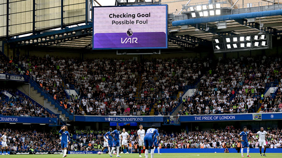 Chelsea players beneath a VAR screen.