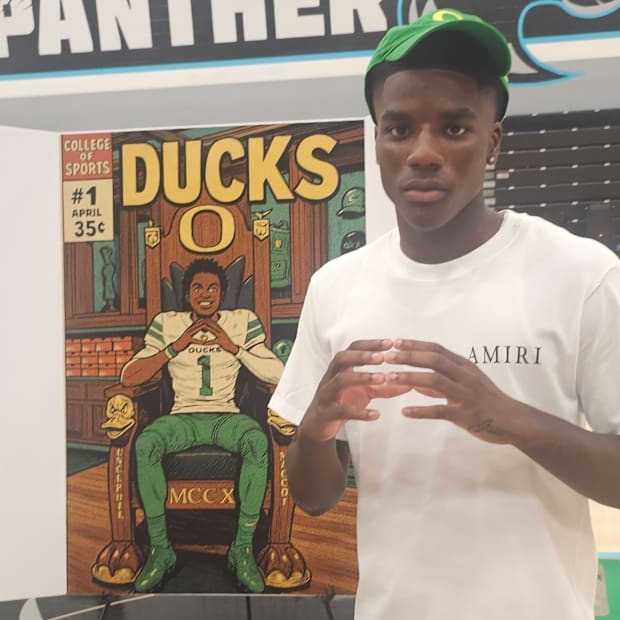 Jalen Lott flashes the "O" sign in front a poster depicting him in an Oregon uniform sitting on a Ducks throne.