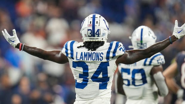 A Colts defensive player (Chris Lammons) stands with his arms out while wearing a white helmet and jersey during a game. 