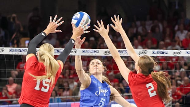 Creighton middle blocker Kiara Reinhardt tips a shot past Nebraska middle blocker Andi Jackson and setter Bergen Reilly.