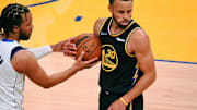 Golden State Warriors guard Stephen Curry holds the ball after a play Jalen Brunson reaches in. 