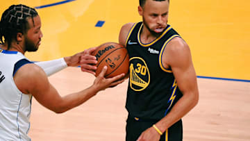 Golden State Warriors guard Stephen Curry holds the ball after a play Jalen Brunson reaches in. 