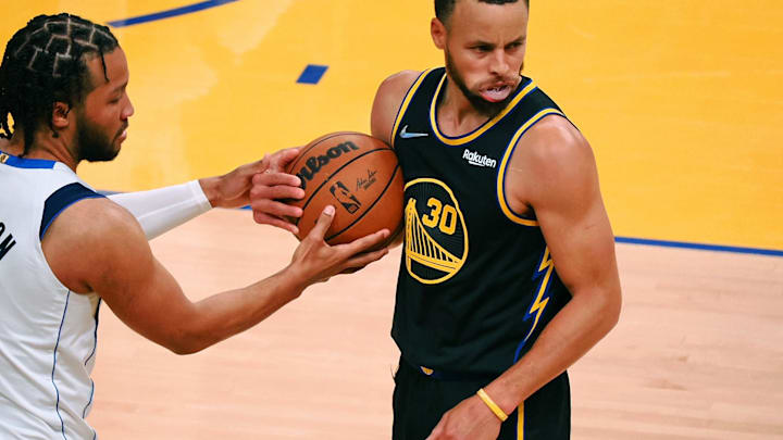 Golden State Warriors guard Stephen Curry holds the ball after a play Jalen Brunson reaches in. 