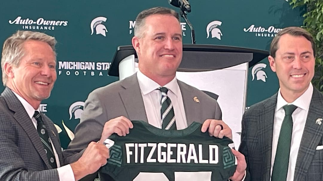 Michigan State Spartans head coach Pat Fitzgerald, center, poses with a namesake jersey next to MSU president Kevin Guskiewicz, left, and athletic director J Batt, right, during Fitzgerald's introductory press conference on Tuesday, Dec. 2, 2025.