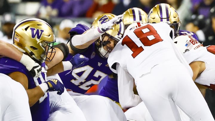 Huskies linebacker Carson Bruener (42) tackles Stanford quarterback Tanner McKee (18) in their 2022 game.