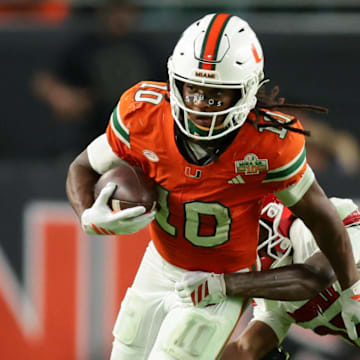 Oct 17, 2025; Miami Gardens, Florida, USA; Miami Hurricanes wide receiver Malachi Toney (10) carries the football against Louisville Cardinals defensive back Tayon Holloway (25) during the fourth quarter at Hard Rock Stadium. Mandatory Credit: Sam Navarro-Imagn Images