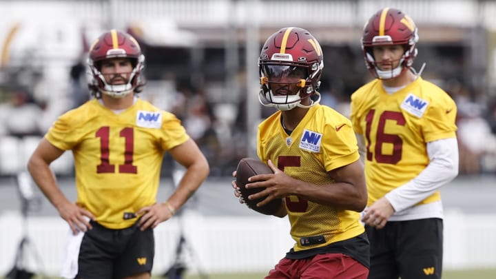 Jul 26, 2024; Ashburn, VA, USA; Washington Commanders quarterback Jayden Daniels (5) prepares to pass the ball as Commanders quarterbacks Sam Hartman (11) and Jeff Driskel (16) look on during day three of training camp at Commanders Park. Mandatory Credit: Geoff Burke-USA TODAY Sports