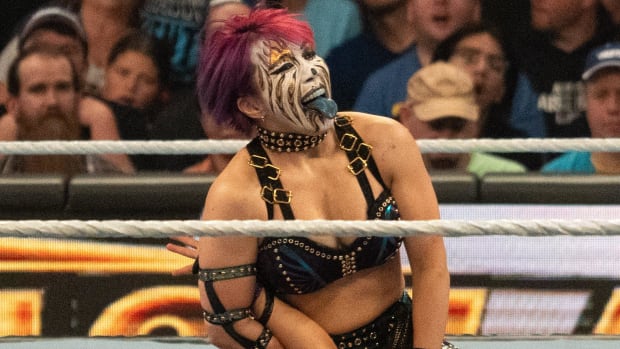 Asuka kneels on Iyo Sky during the triple threat women's championship match of the WWE Fastlane pro wrestling event.