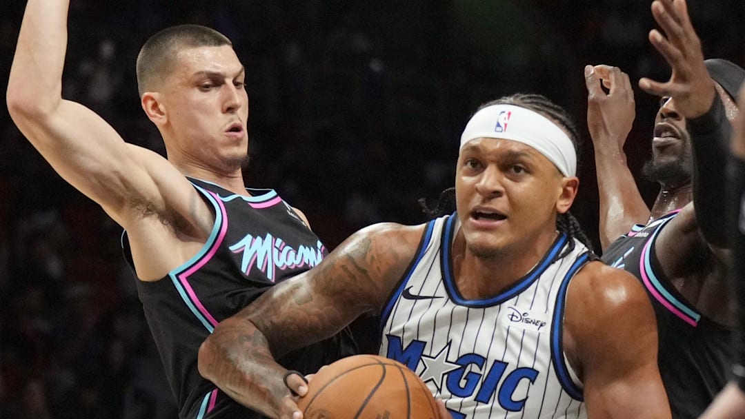 Mar 14, 2026; Miami, Florida, USA;  Orlando Magic forward Paolo Banchero (5) splits the defense of Miami Heat guard Tyler Herro (14) and Miami Heat center Bam Adebayo (13) during the first half at Kaseya Center. Mandatory Credit: Jim Rassol-Imagn Images
