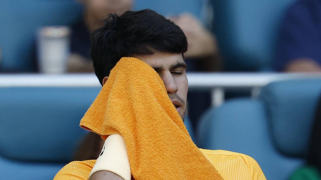 Carlos Alcaraz wipes his face in his player's chair