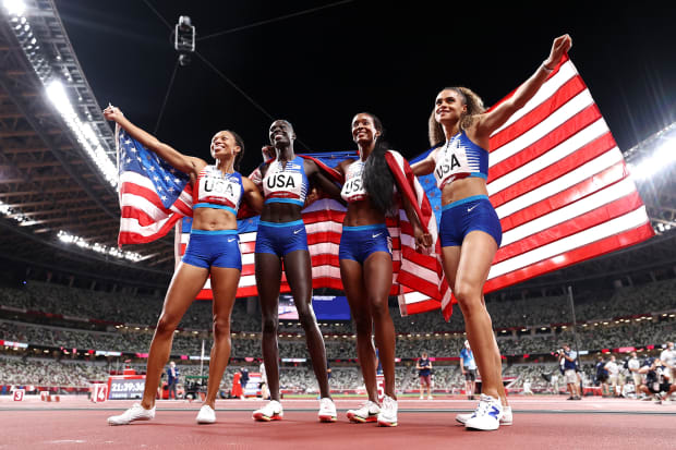 Allyson Felix, Athing Mu, Dalilah Muhammad and Sydney McLaughlin of hold the American flag at the Tokyo Olympics. 