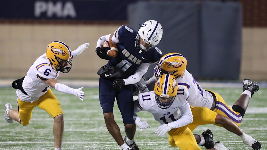 Hoban's Payton Cook looks for yardage as Avon defenders Jacob Graham, left, Jakob Weatherspoon and Jeremiah Kelly converge during the Division II state semifinal, Friday, Nov. 29, 2024.