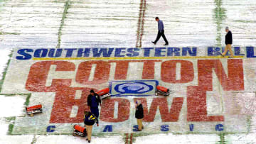 Cotton Bowl officials worked Monday morning to clear snow from the field from a 1/2-inch snow and