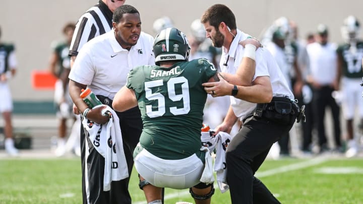 Michigan State's Nick Samac is helped up after an injury during the fourth quarter in the game