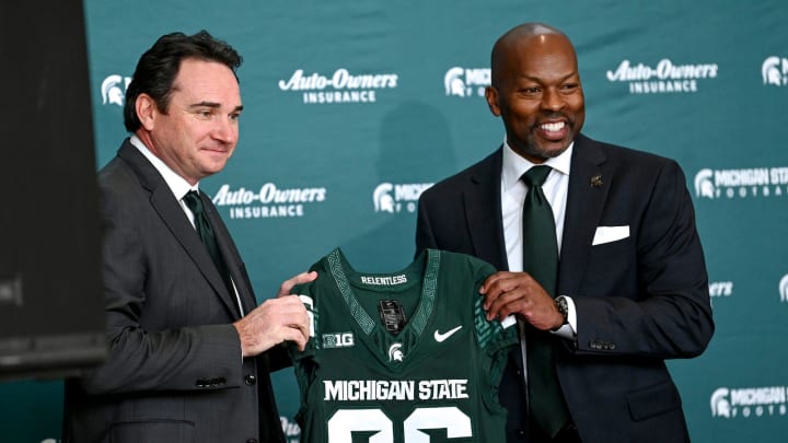 Michigan State football coach Jonathan Smith, left, and athletic director Alan Haller pose with a jersey during an introductory press conference for the new coach on Tuesday, Nov. 28, 2023, at the Breslin Center in East Lansing.