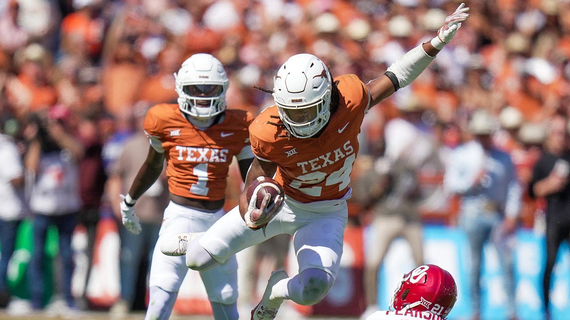 Texas Longhorns running back Jonathon Brooks (24) jumps over an Oklahoma Sooners defensive back.