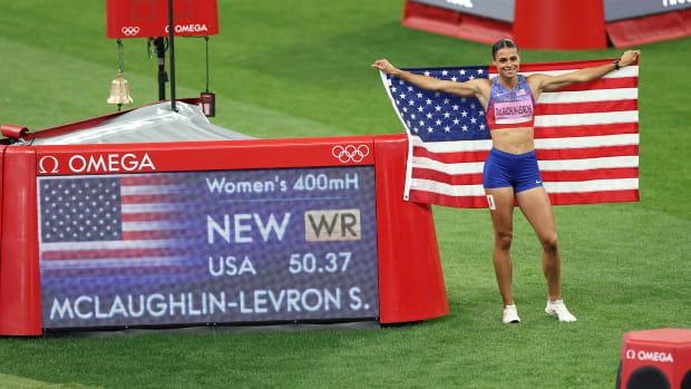 Sydney McLaughlin-Levrone poses with an American flag and time board, displaying her world record in the 400-meter hurdles.