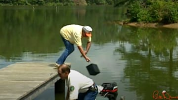 Seen in this screengrab of archival footage from his TV show, Bill Dance falls into a lake, pulled in by the weight of a marine battery. The video clip of this moment is one of the best Bill Dance bloopers of all time.
