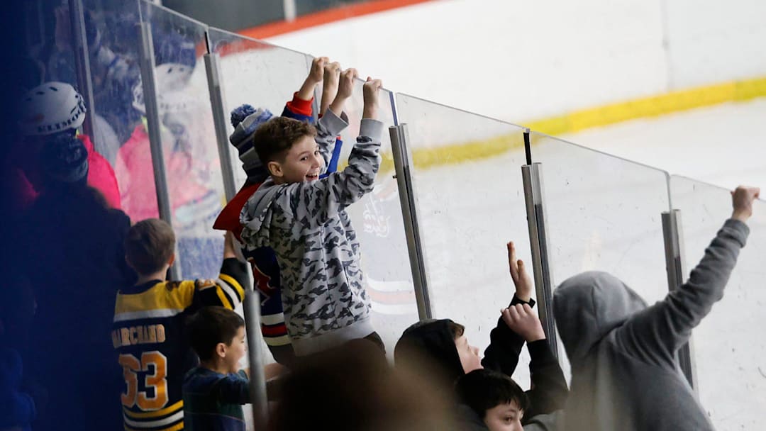 Kids hang on the glass, watching a high school hockey game at Zapustas Rink on Wednesday, February 26, 2025