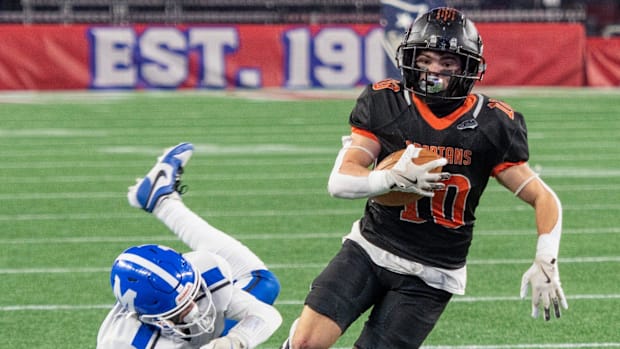 Uxbridge wide receiver Josh Johnson catches a pass and shakes off the tackle from Mashpee’s Maxx Smith for a first down at Gi