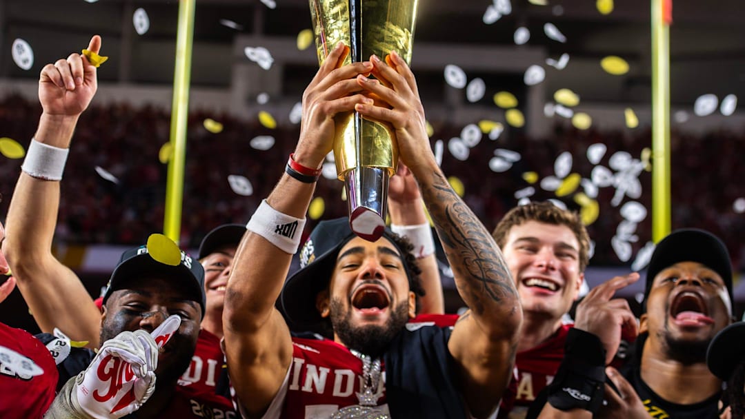 Indiana's Elijah Sarratt (13) lifts the trophy as Tyrique Tucker (95), Charlie Becker (80), Fernando Mendoza (15), and Mikail Kamara (6) celebrate on the podium after the College Football Playoff National Championship college football game at Hard Rock Stadium in Miami Gardens on Monday, Jan. 19, 2026. Indiana's Elijah Sarratt (13) lifts the trophy as Tyrique Tucker (95), Charlie Becker (80), Fernando Mendoza (15), and Mikail Kamara (6) celebrate on the podium after the College Football Playoff National Championship college football game at Hard Rock Stadium in Miami Gardens on Monday, Jan. 19, 2026.