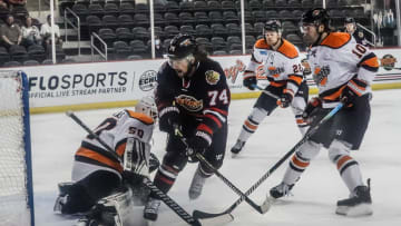The Indy Fuel's Keoni Texeira (74) shoots around Fort Wayne Komets goalie, Stefanos Lekkas (50) on Friday, April 9, 2021, during a game at the State Farm Coliseum in Indianapolis. Right, Fort Wayne Komets Matt Murphy (22) and Nick Boka (10).