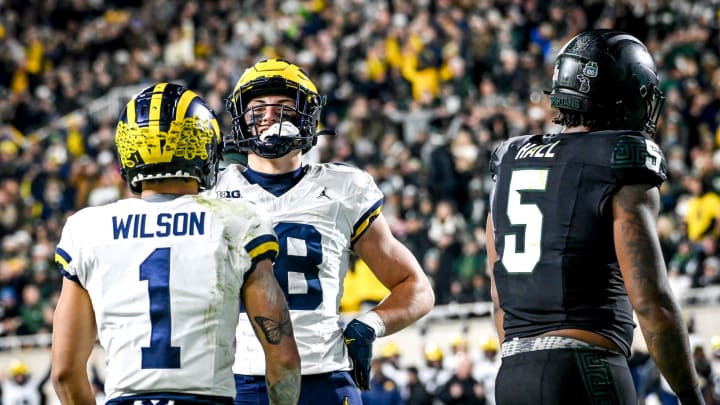 Michigan's Colston Loveland, center, poses like Paul Bunyan while celebrating his touchdown with teammate Roman Wilson as Michigan State's Jordan Hall, right, looks on during the second quarter on Saturday, Oct. 21, 2023, at Spartan Stadium in East Lansing.