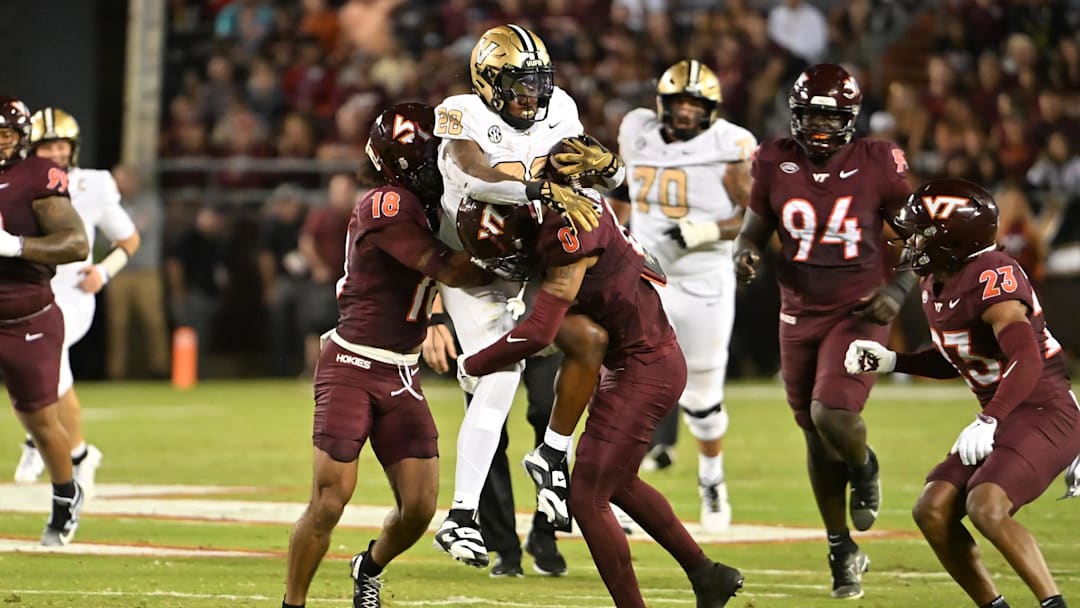 Virginia Tech Hokies safety Isaiah Cash (18) and Virginia Tech Hokies safety Quentin Reddish (0) tackle Vanderbilt Commodores running back Sedrick Alexander (28)