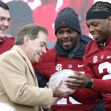 Alabama running back Derrick Henry (2) hands the Crystal trophy to coach Nick Saban, with offensive lineman Ryan Kelly (70) and linebacker Reggie Ragland (19), during a presentation to celebrate the victory in the CFP National Championship game at Bryant-Denny Stadium. 