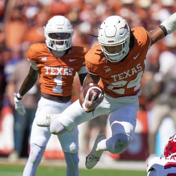 Texas Longhorns running back Jonathon Brooks (24) jumps over Oklahoma Sooners defensive back Reggie Pearson (21) for the first down in the third quarter during an NCAA college football game at the Cotton Bowl on Saturday, Oct. 7, 2023 in Dallas, Texas. This game makes up the119th rivalry match up.