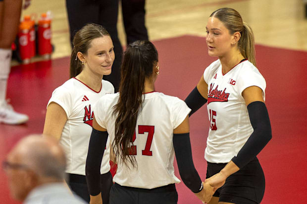 Nebraska setter Bergen Reilly, outside hitter Harper Murray, and middle blocker Andi Jackson converse.