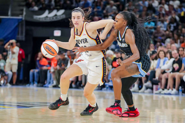 Indiana Fever guard Caitlin Clark moves around a Chicago Sky player while dribbling the ball. 