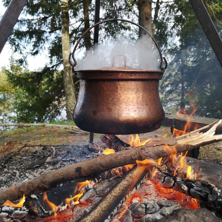 huge copper cauldron suspended over a campfire