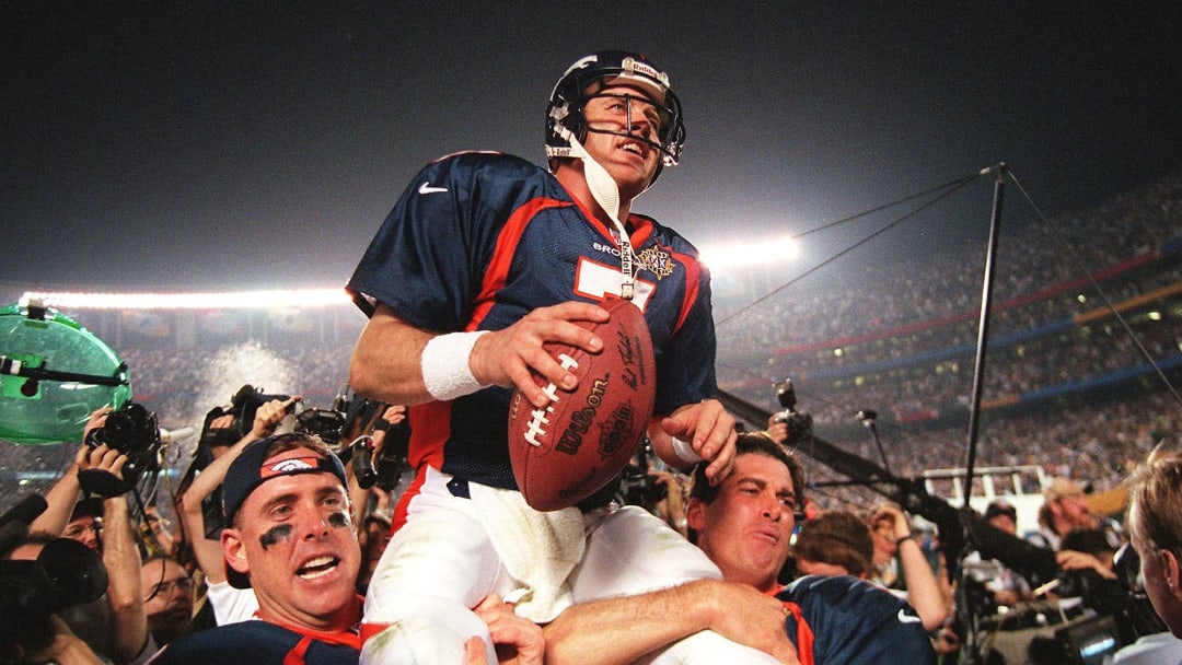 Denver Broncos quarterback John Elway (C) is carri